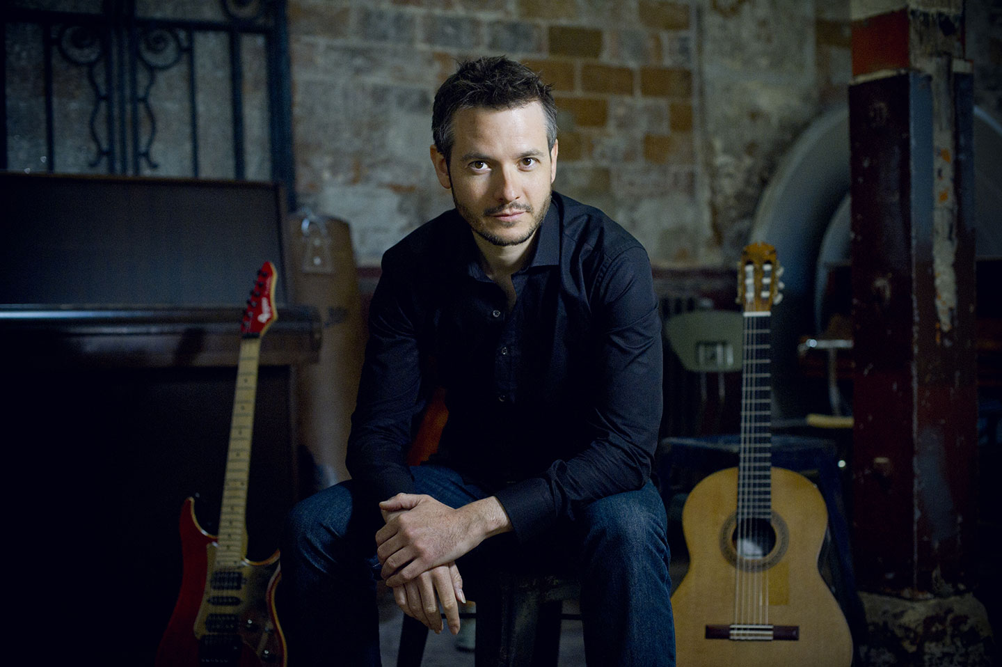 Pierre Bibault pose devant ses guitares