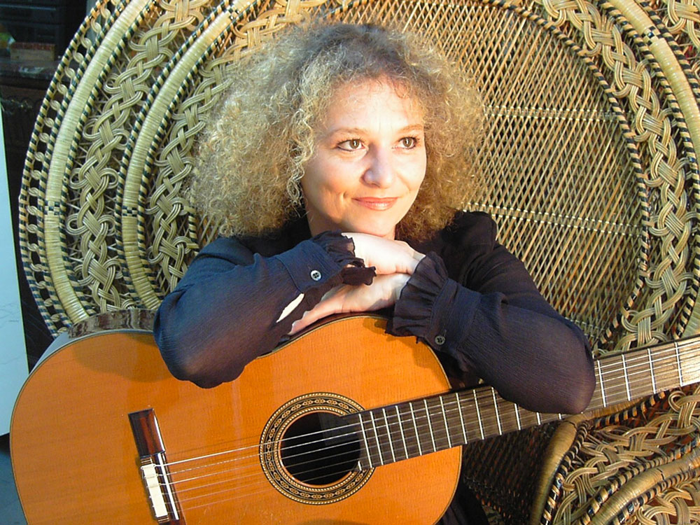Valérie Duchâteau assise avec sa guitare